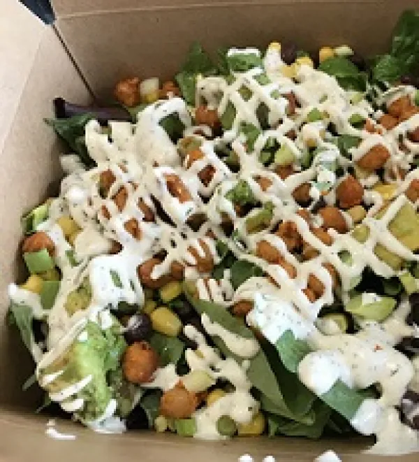 A round pizza looking piece of food that looks like beans and crisscross dribbles of white cream