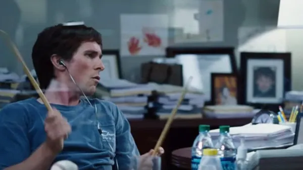 Picture of a guy in an office playing with drumsticks