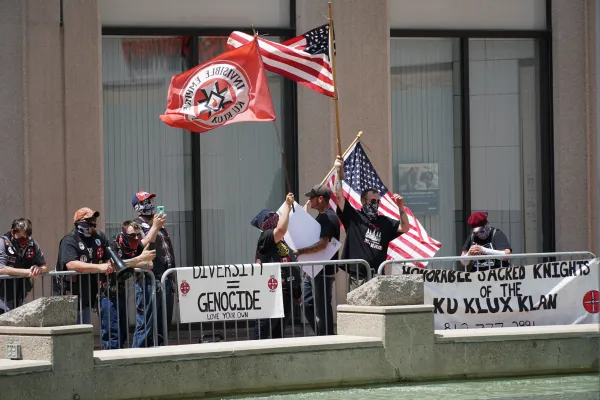 Guys waving flags and with Ku Klux Klan signs