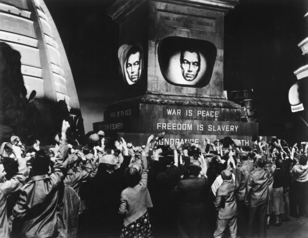 People raising fists to a man's image with words War is Peace