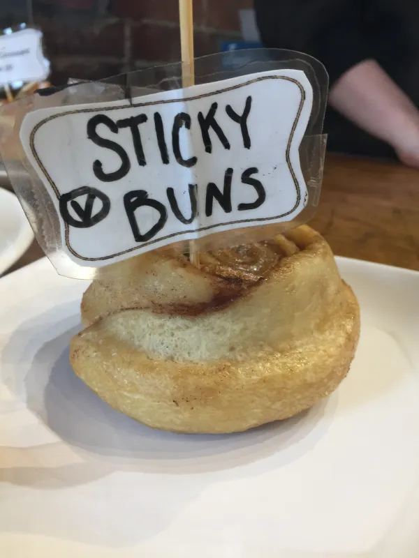 A cinnamon bun with a sign on it saying Sticky Buns