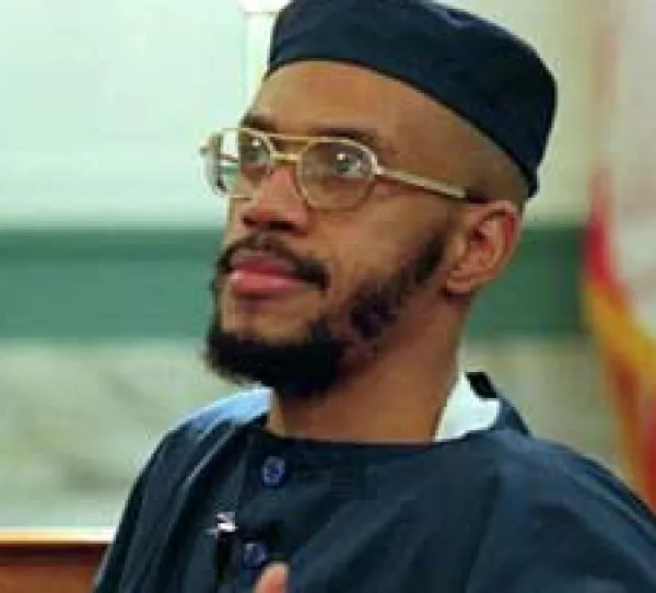 Black man with wire-rimmed glasses and a mustache and beard